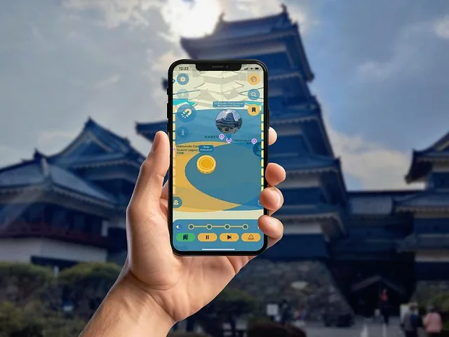 Main tenant un téléphone affichant une application avec une carte devant le château de Matsumoto
