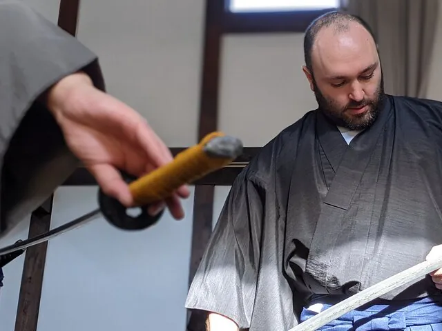 Man in traditional samurai clothing holding a sword in a room