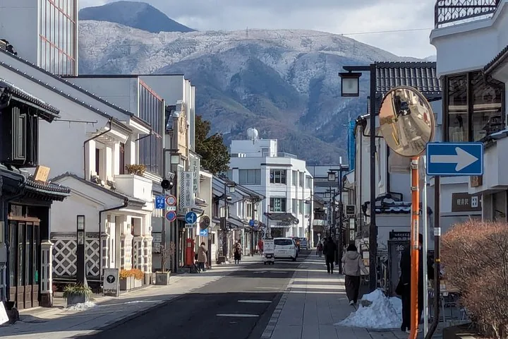 Vue de la rue avec des bâtiments traditionnels et des montagnes enneigées en arrière-plan