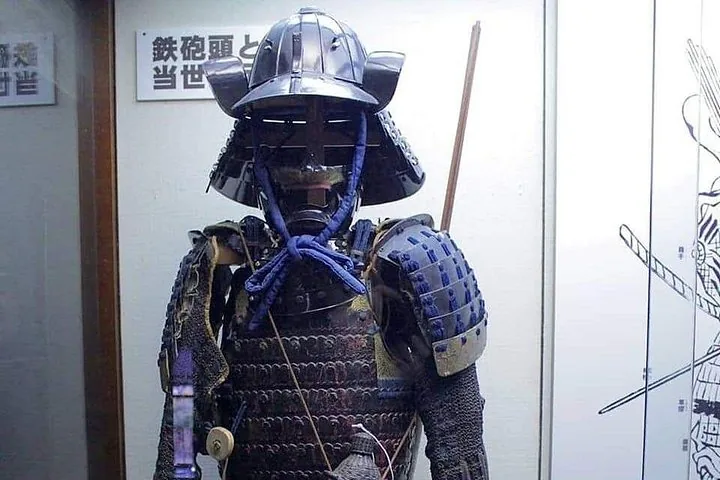 Antike Samurai-Rüstung, die drinnen neben einer Zeichnung ausgestellt ist