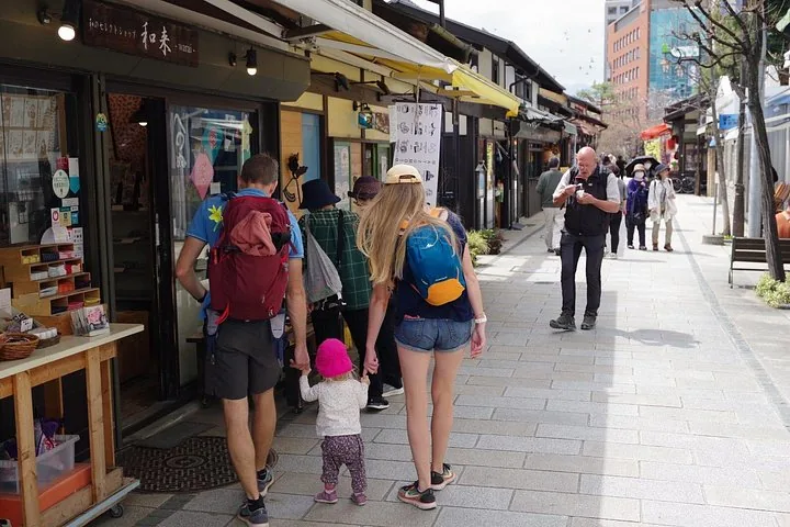 Family holding hands walking down a street with traditional shops